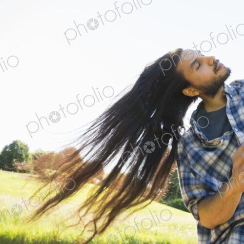 Young man shaking out his very long black hair