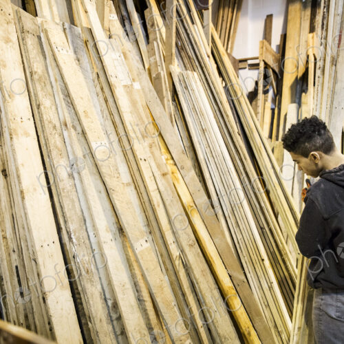 Young man standing next to a stack of wooden planks in a warehouse. Young man standing next to a stack of wooden planks in a warehouse.