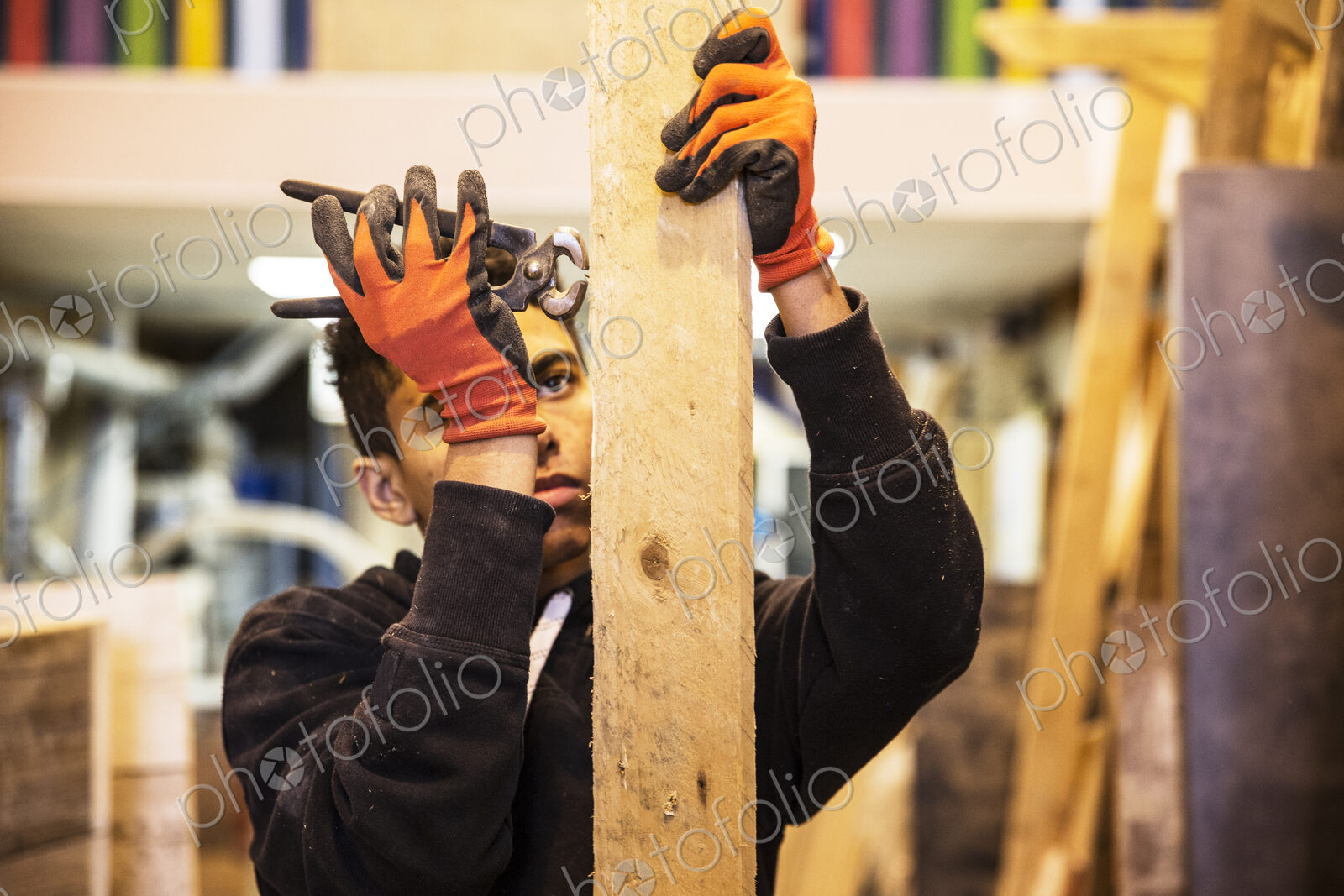 Young man wearing work gloves standing in warehouse, removing rusty nails from…
