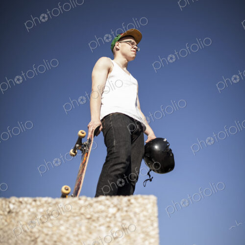 Young man with skateboard standing on top of half pipe in skate park. Young man with skateboard standing on top of half pipe in skate park.