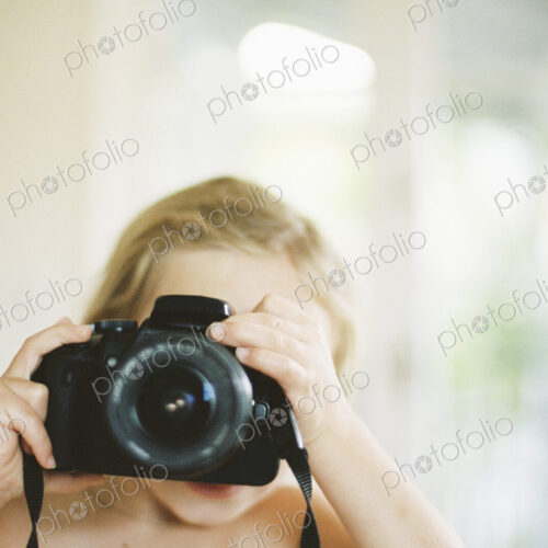 Young nude girl taking a picture with a camera.