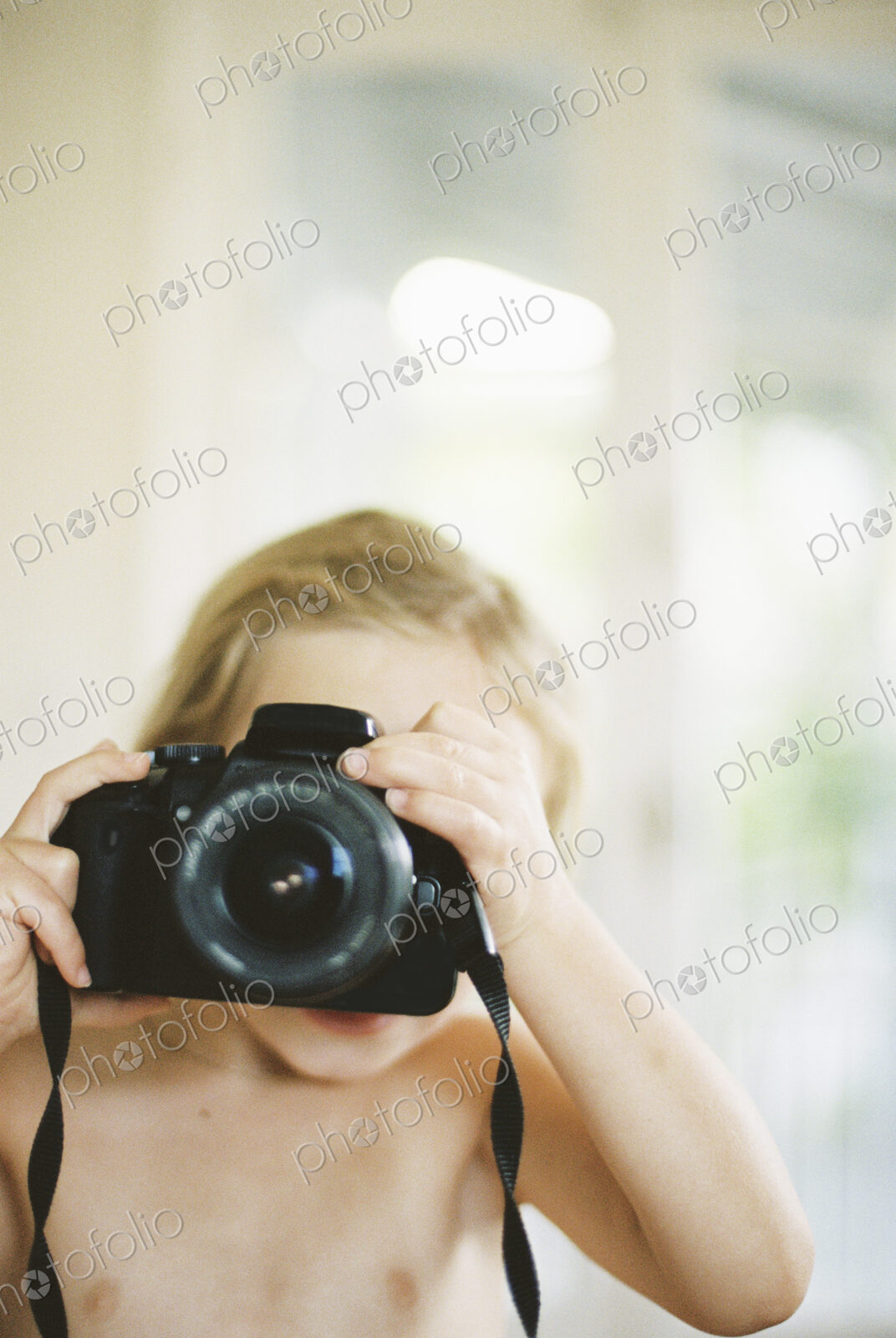 Young nude girl taking a picture with a camera.