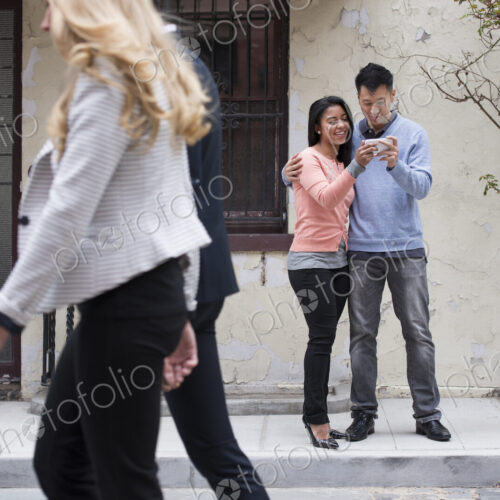 Young people outdoors on the city streets in springtime. A couple taking images of… Young people outdoors on the city streets in springtime. A couple taking images of…
