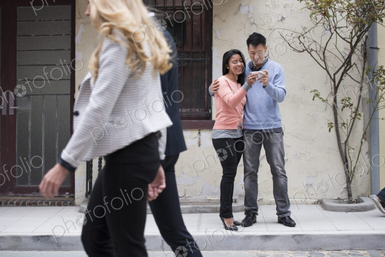 Young people outdoors on the city streets in springtime. A couple taking images of…