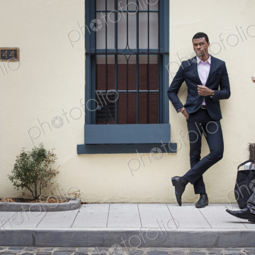 Young people outdoors on the city streets in springtime. A man leaning against a wall… Young people outdoors on the city streets in springtime. A man leaning against a wall…