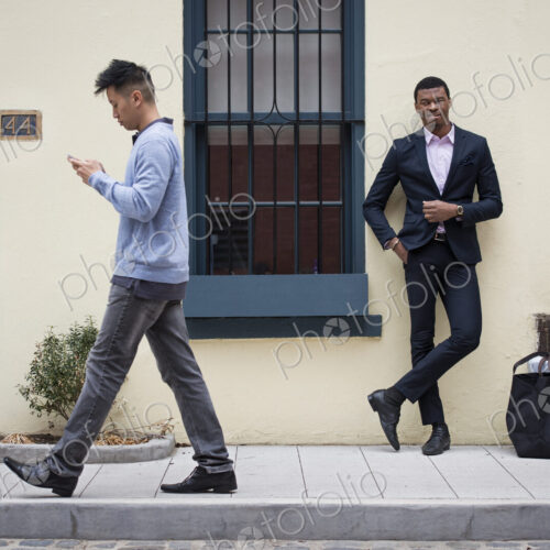 Young people outdoors on the city streets in springtime. A man leaning against a wall… Young people outdoors on the city streets in springtime. A man leaning against a wall…