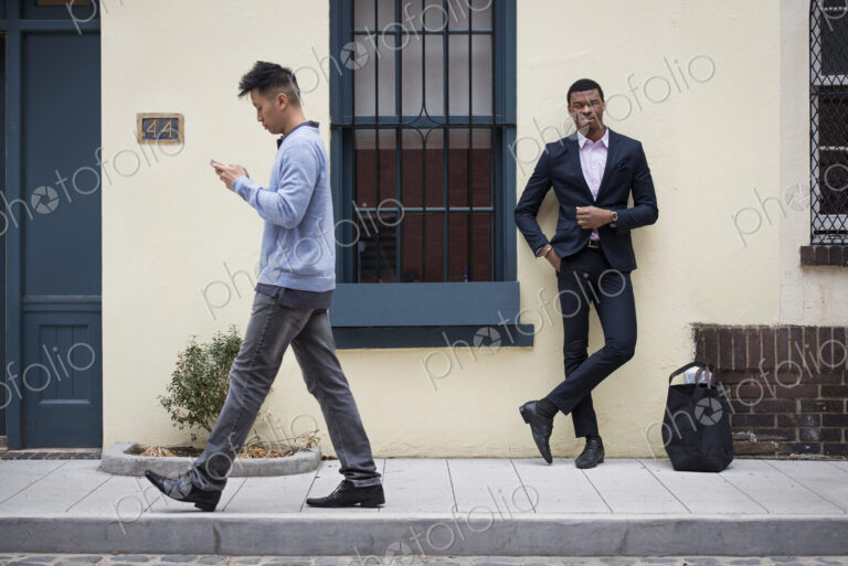 Young people outdoors on the city streets in springtime. A man leaning against a wall…