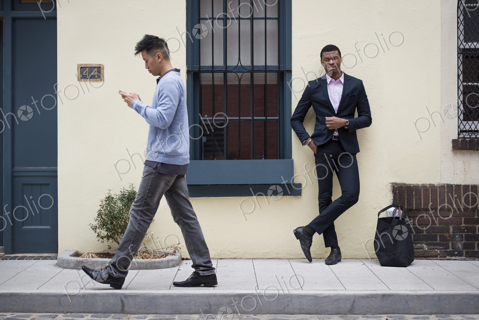 Young people outdoors on the city streets in springtime. A man leaning against a wall…
