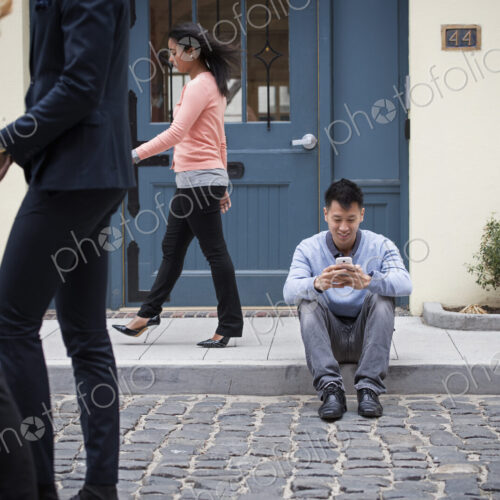 Young people outdoors on the city streets in springtime. A man sitting on the ground… Young people outdoors on the city streets in springtime. A man sitting on the ground…