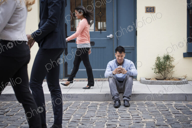Young people outdoors on the city streets in springtime. A man sitting on the ground…