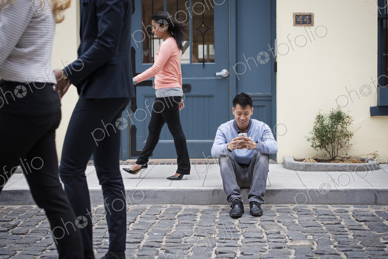 Young people outdoors on the city streets in springtime. A man sitting on the ground…