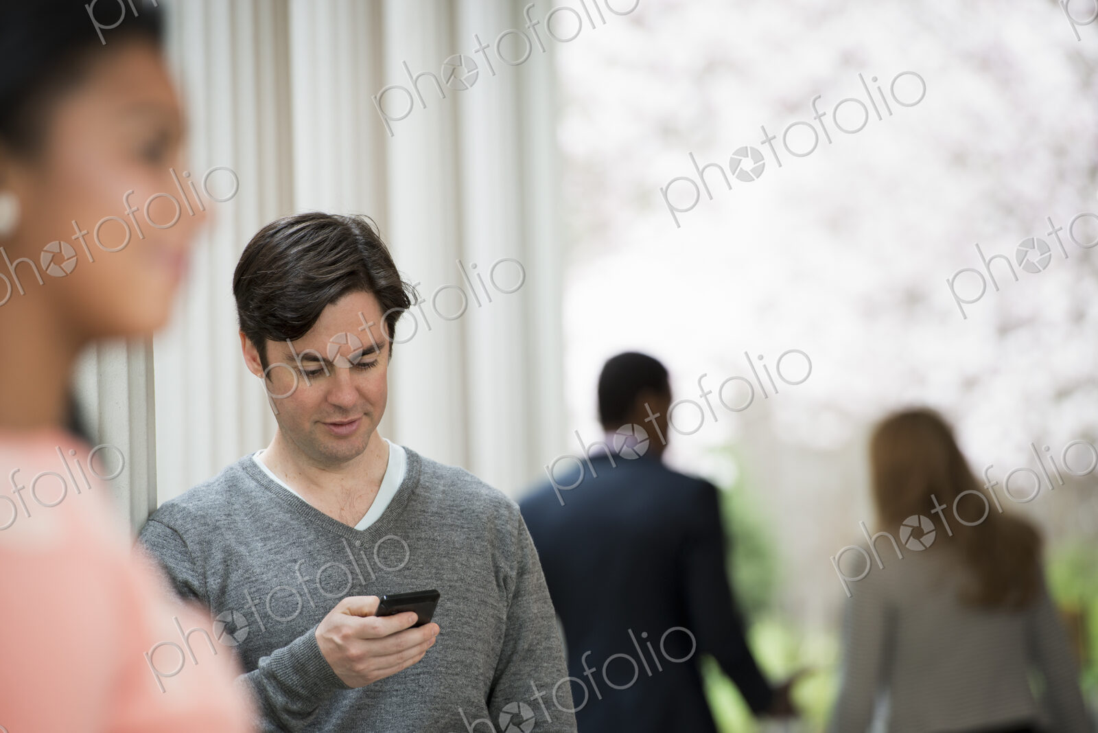 Young people outdoors on the city streets in springtime. Men and women.Two people, one…