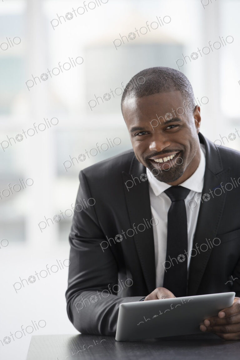 Young professionals at work. A man in a suit, sitting using a digital tablet.