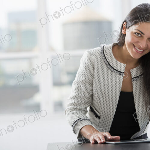 Young professionals at work. A woman at a work table using a digital tablet. Looking… Young professionals at work. A woman at a work table using a digital tablet. Looking…
