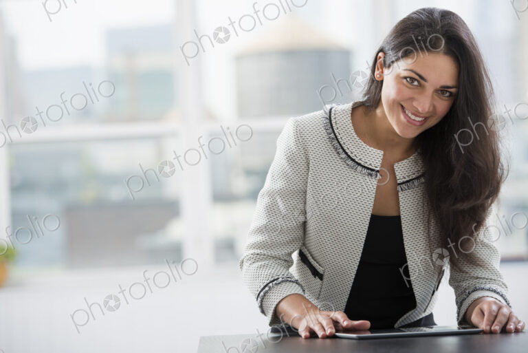 Young professionals at work. A woman at a work table using a digital tablet. Looking…
