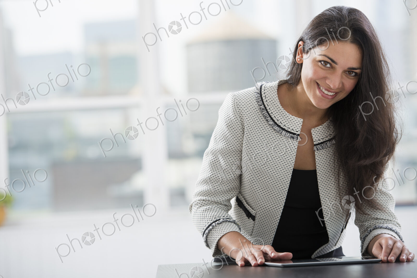 Young professionals at work. A woman at a work table using a digital tablet. Looking…