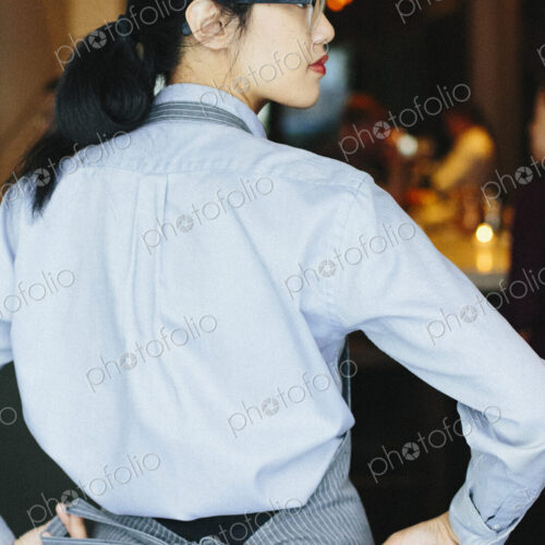 Young waitress tying her apron at a city restaurant.