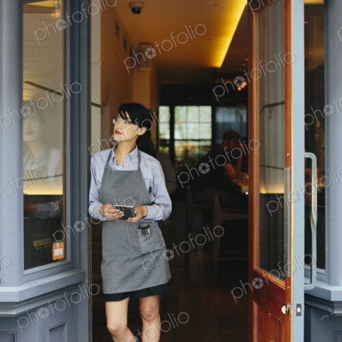 Young waitress wearing an apron at a city restaurant.