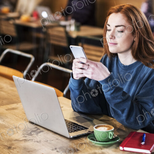 Young woman in a cafe working, using laptop and smart phone Young woman in a cafe working, using laptop and smart phone