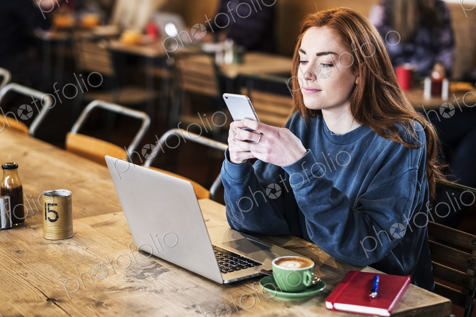 Young woman in a cafe working, using laptop and smart phone