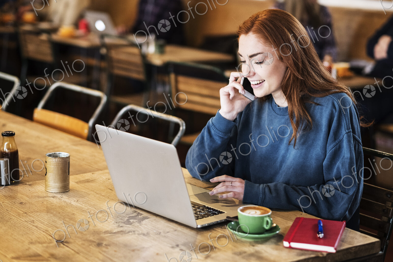 Young woman in a cafe working, using laptop and smart phone