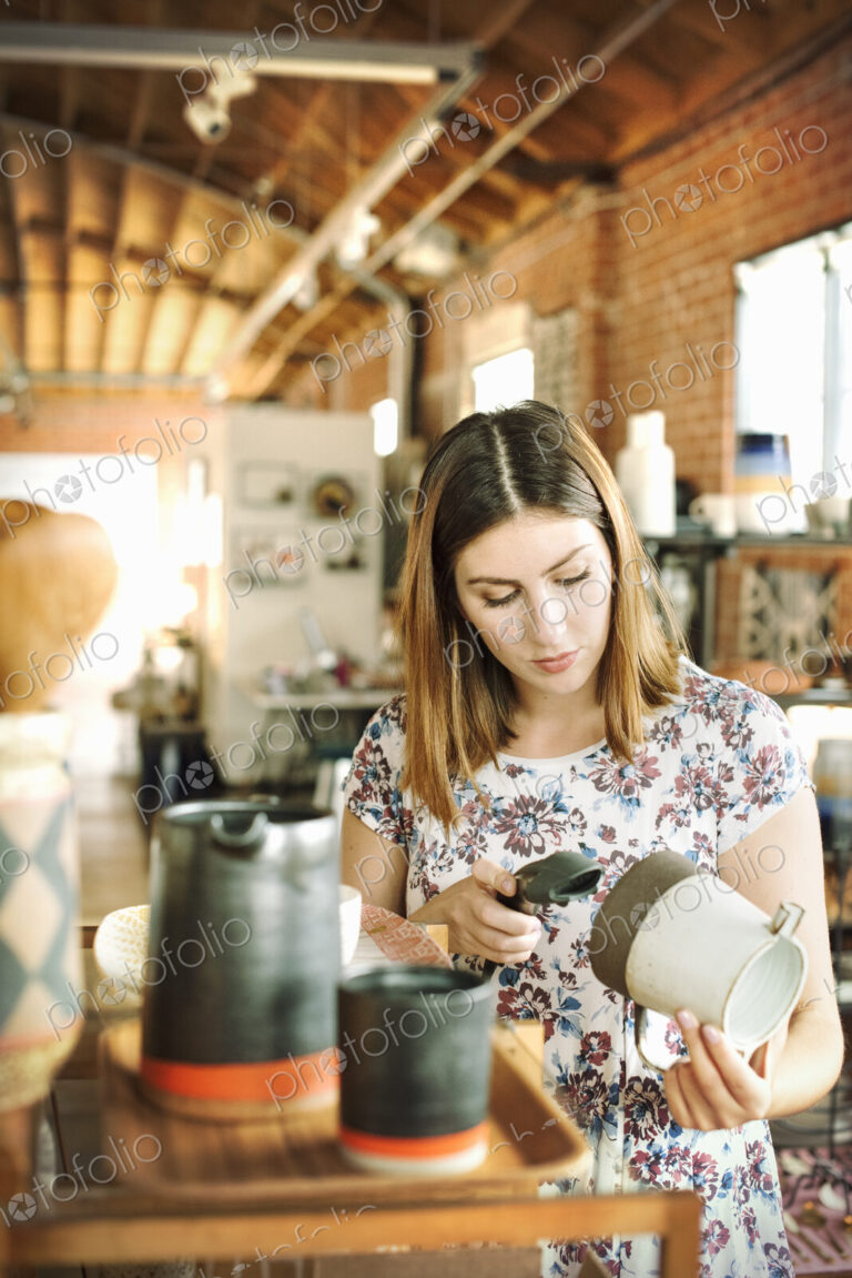Young woman in a shop, scanning the barcode of a ceramic jug with a barcode scanner.