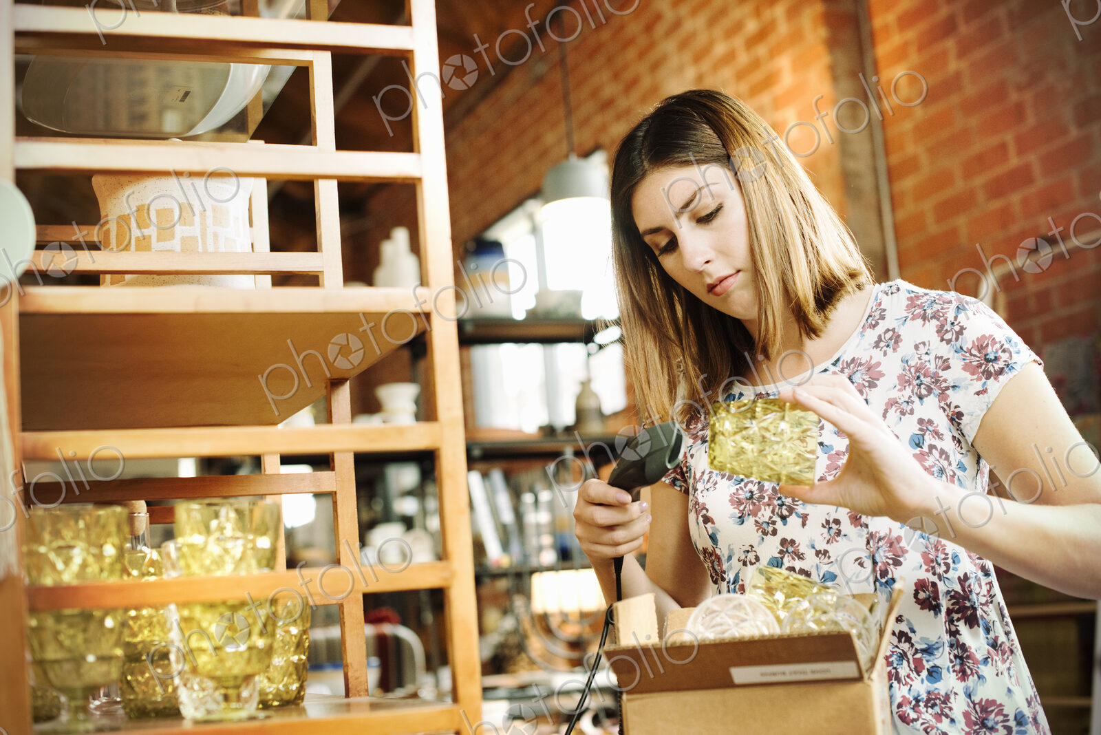 Young woman in a shop, scanning the barcode of a drinking glass with a barcode scanner.
