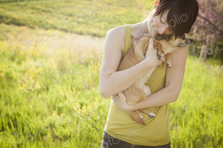 Young woman in grassy field in spring holding dog