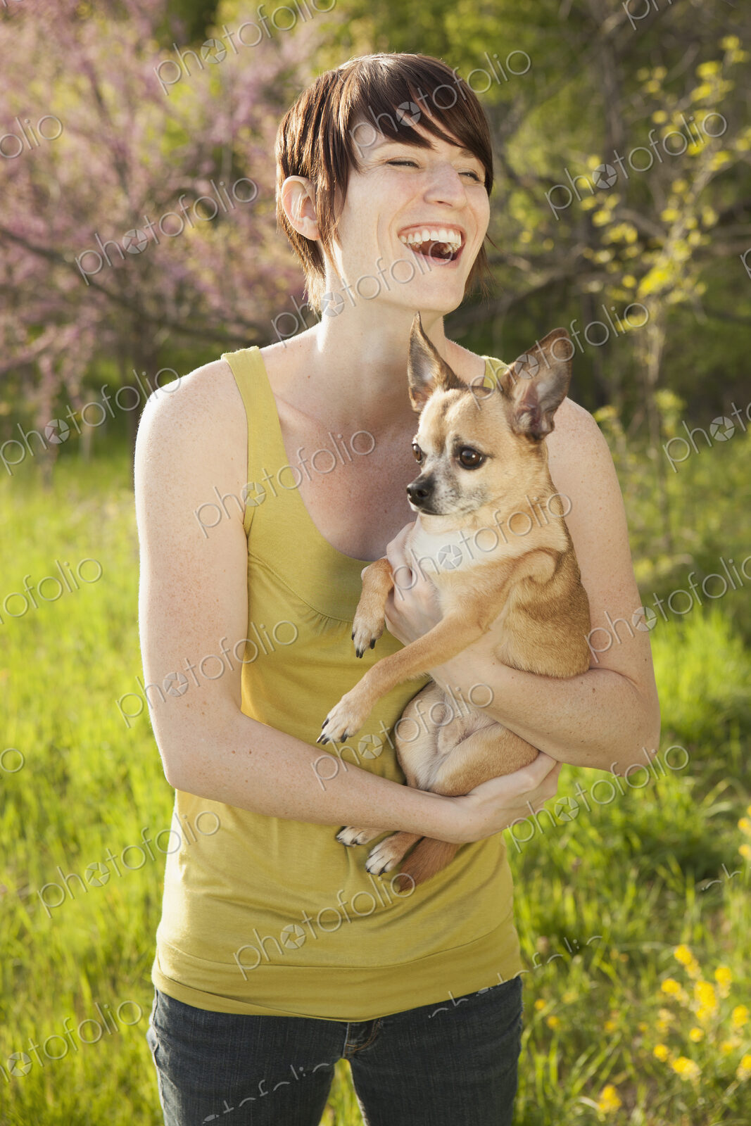 Young woman in grassy field in spring holding dog