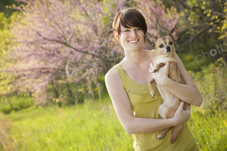 Young woman in grassy field in spring holding dog