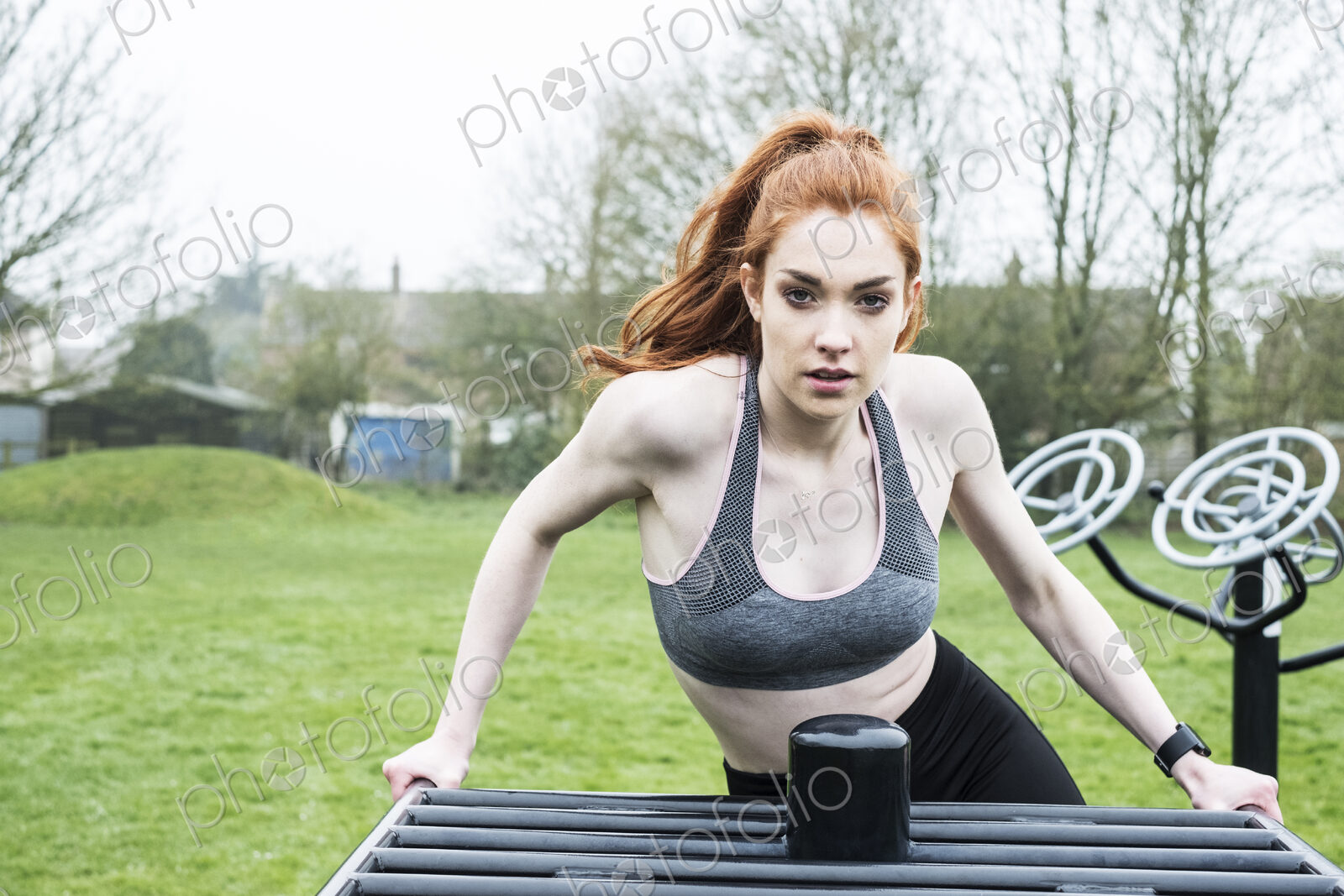 Young woman in sportswear using outdoor exercise equipment