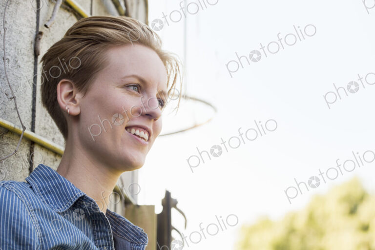Young woman on a working farm, taking a break in the shade of a silo.
