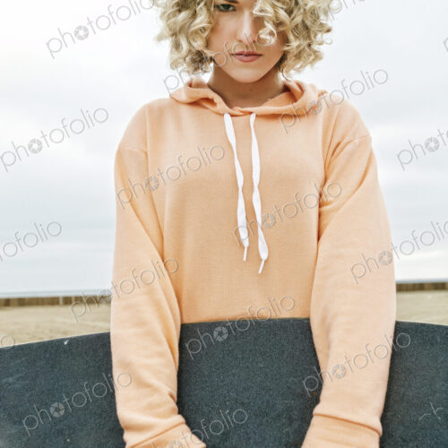 Young woman on sandy beach, holding skateboard, looking at camera. Young woman on sandy beach, holding skateboard, looking at camera.
