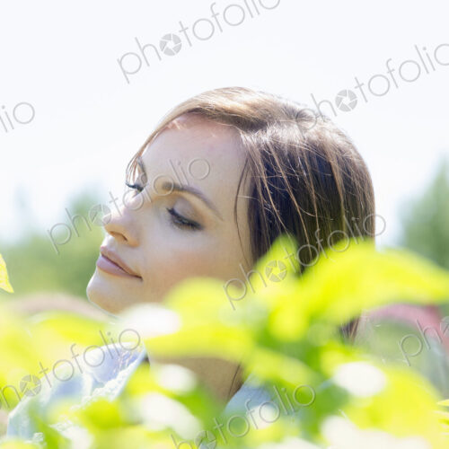 Young woman outdoors surrounded by green plants.