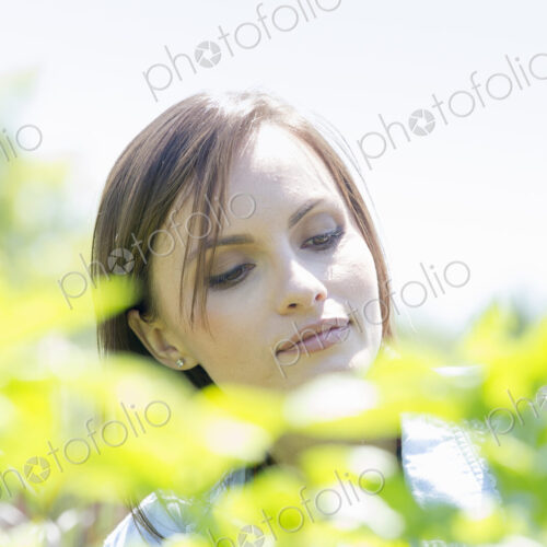 Young woman outdoors surrounded by green plants.
