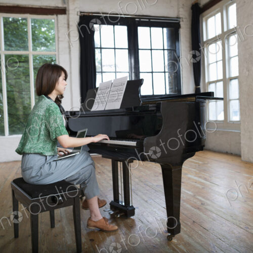 Young woman playing on a grand piano in a rehearsal studio. Young woman playing on a grand piano in a rehearsal studio.
