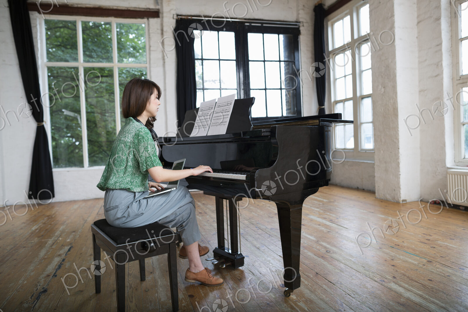 Young woman playing on a grand piano in a rehearsal studio.
