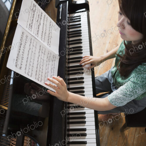 Young woman playing on a grand piano in a rehearsal studio. Young woman playing on a grand piano in a rehearsal studio.