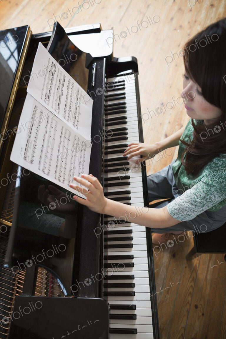 Young woman playing on a grand piano in a rehearsal studio.