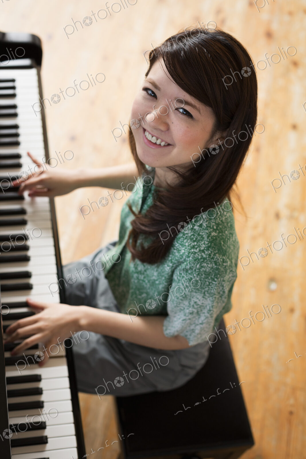 Young woman playing on a grand piano in a rehearsal studio.