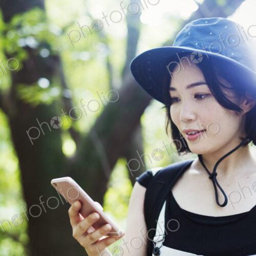 Young woman standing in a forest, using a mobile phone.