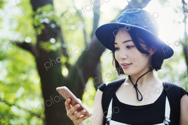 Young woman standing in a forest, using a mobile phone.