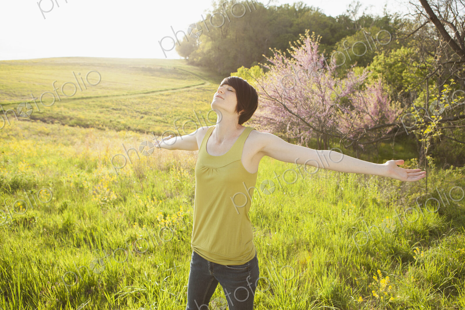 Young woman standing in grassy field in spring.