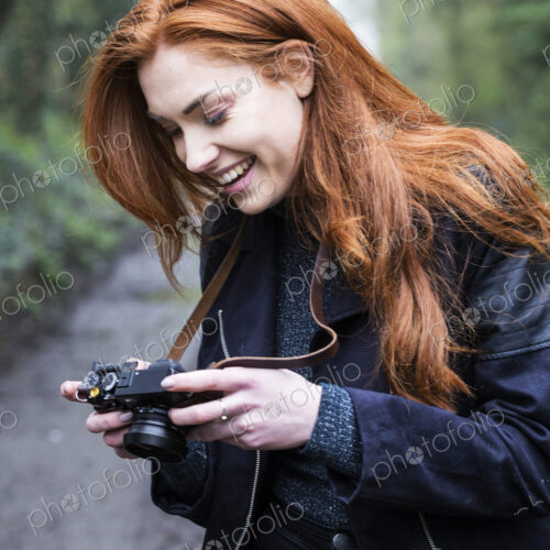 Young woman walking along forest path, with a vintage camera.