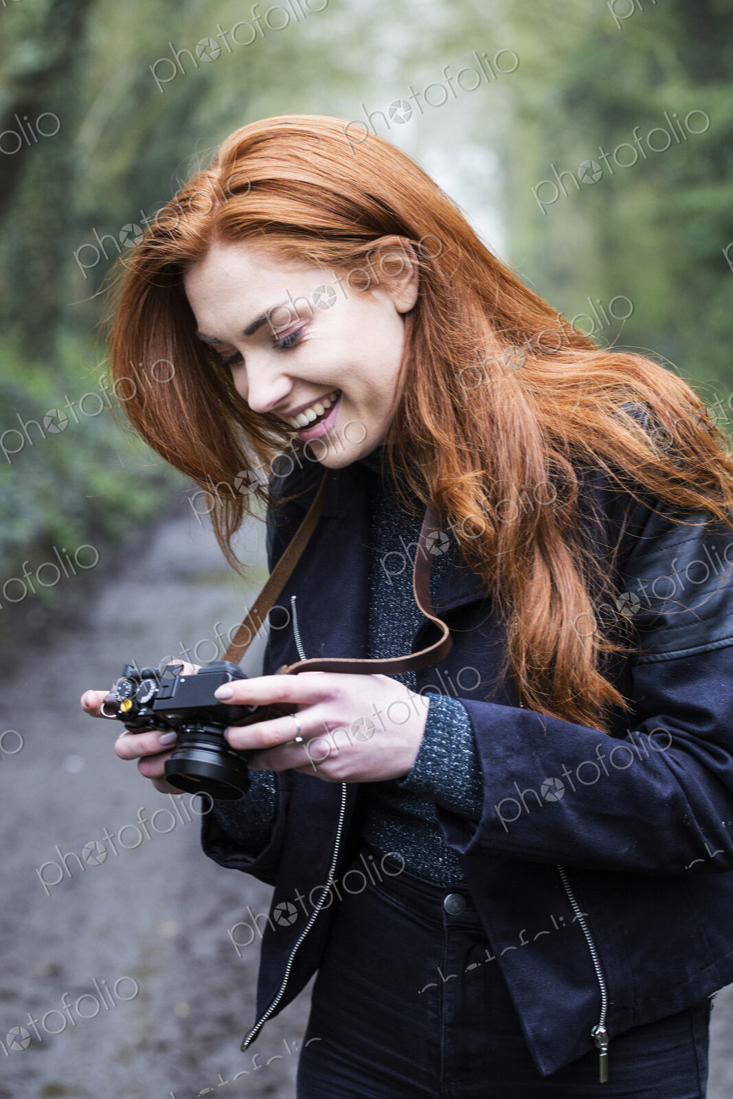 Young woman walking along forest path, with a vintage camera.