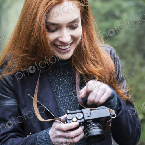 Young woman walking along forest path, with vintage camera.