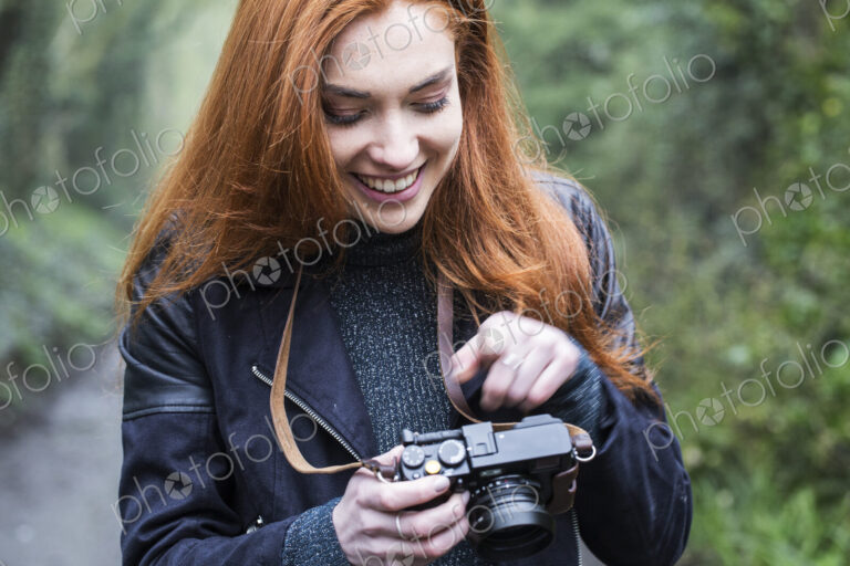 Young woman walking along forest path, with vintage camera.