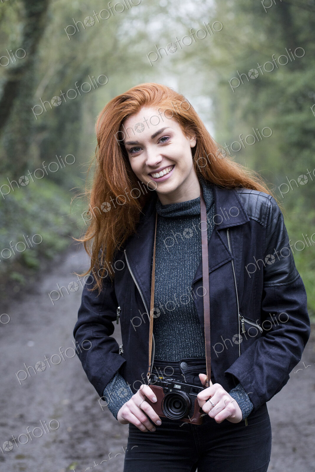 Young woman walking along forest path, with vintage camera.