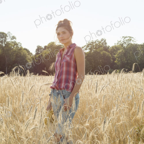 Young woman wearing a checkered shirt standing in a cornfield. Young woman wearing a checkered shirt standing in a cornfield.