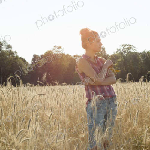 Young woman wearing a checkered shirt standing in a cornfield. Young woman wearing a checkered shirt standing in a cornfield.